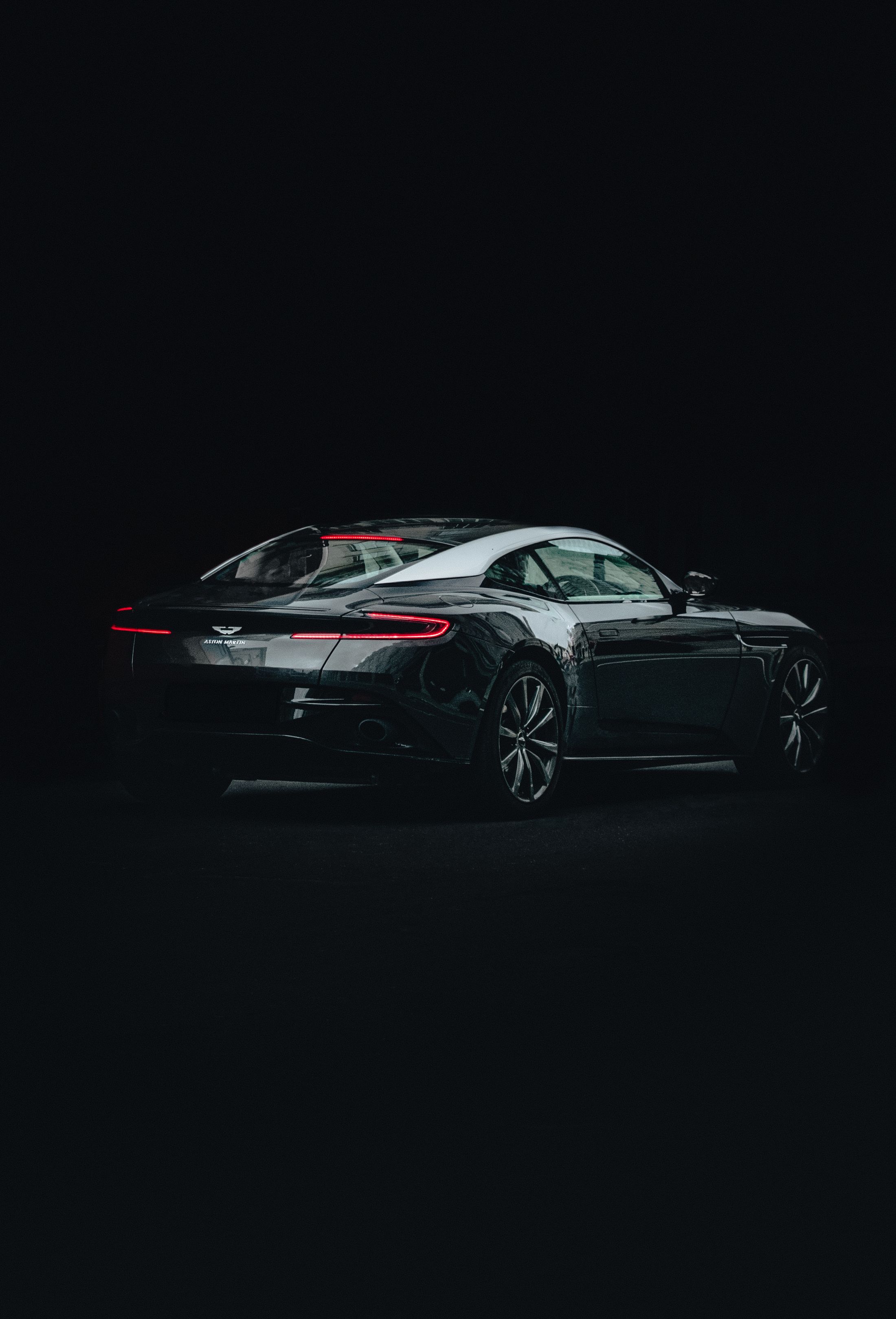 Black Aston Martin in a dark studio, shown in full profile