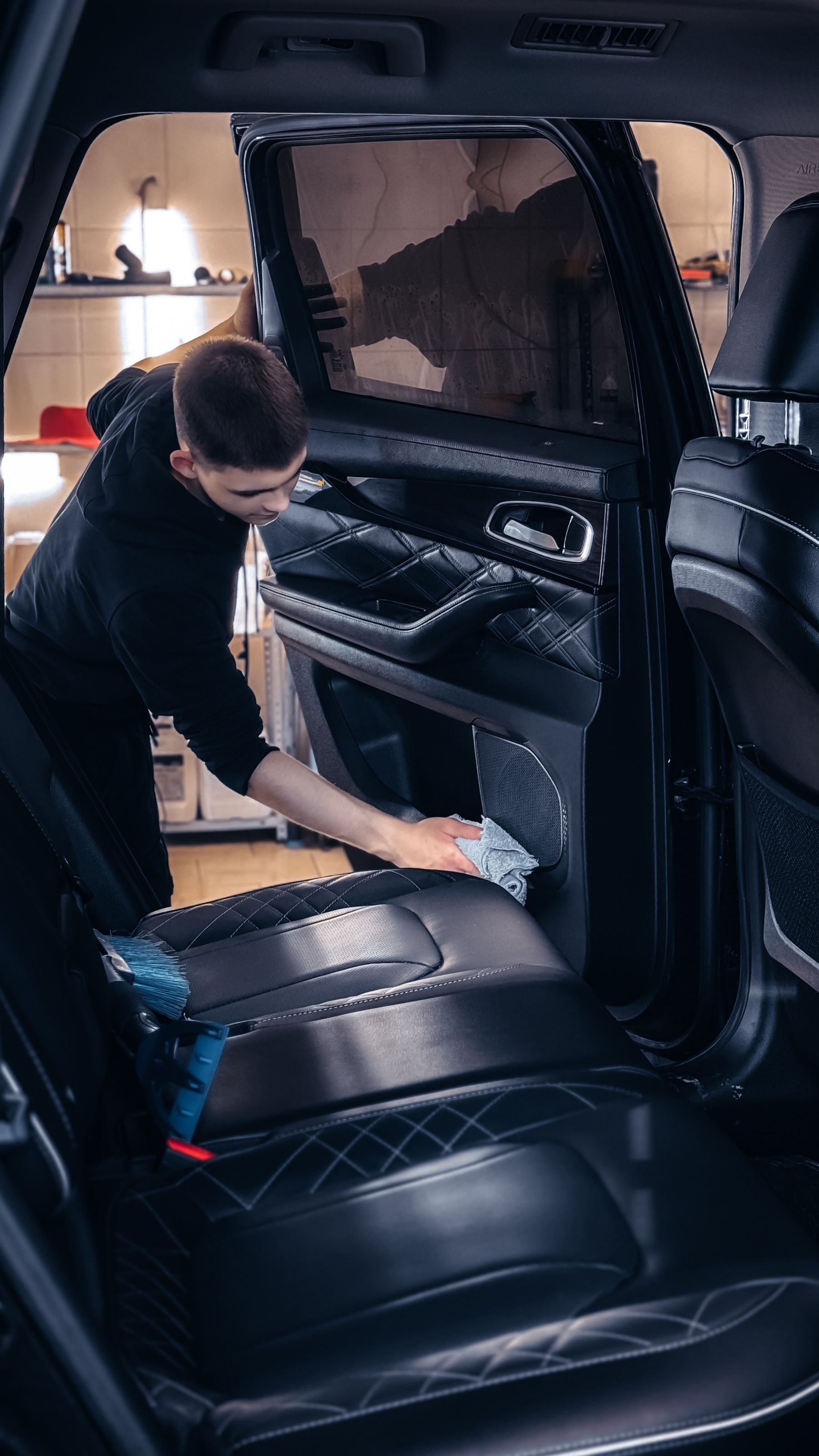 Detailer cleaning the leather trim and seats inside a vehicle