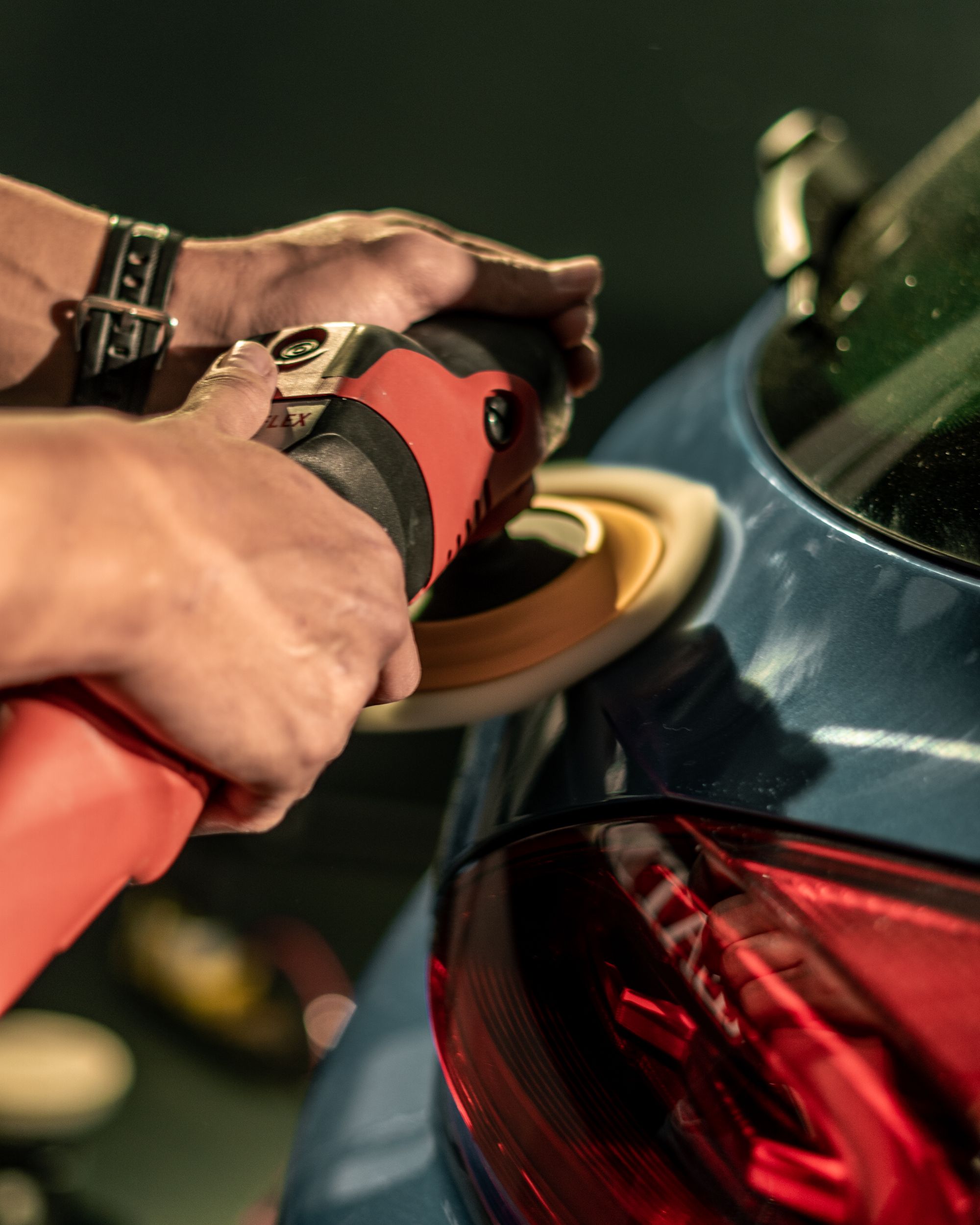 Detailer carefully machine polishing a dark vehicle