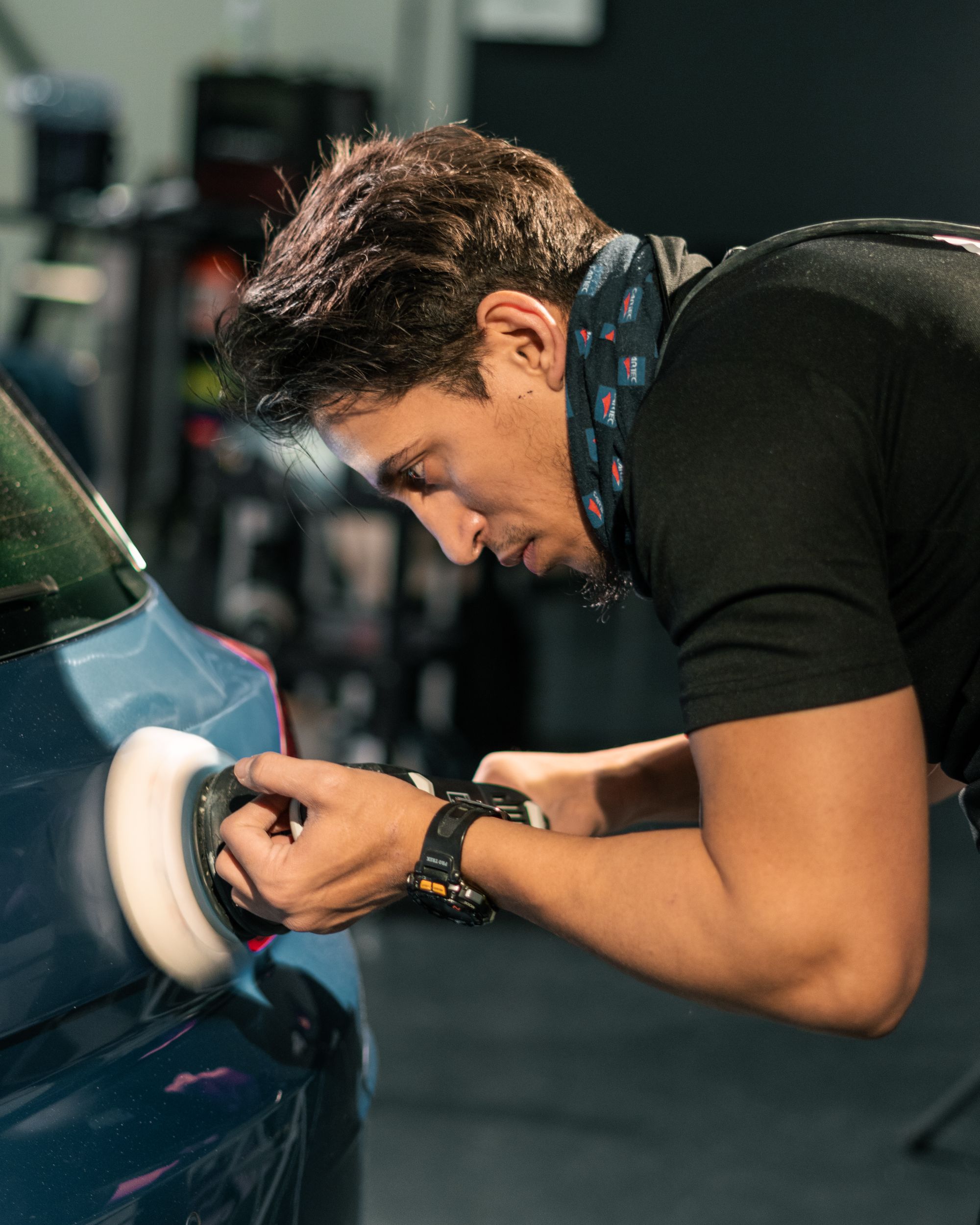 Detailer working carefully across a dark paint finish