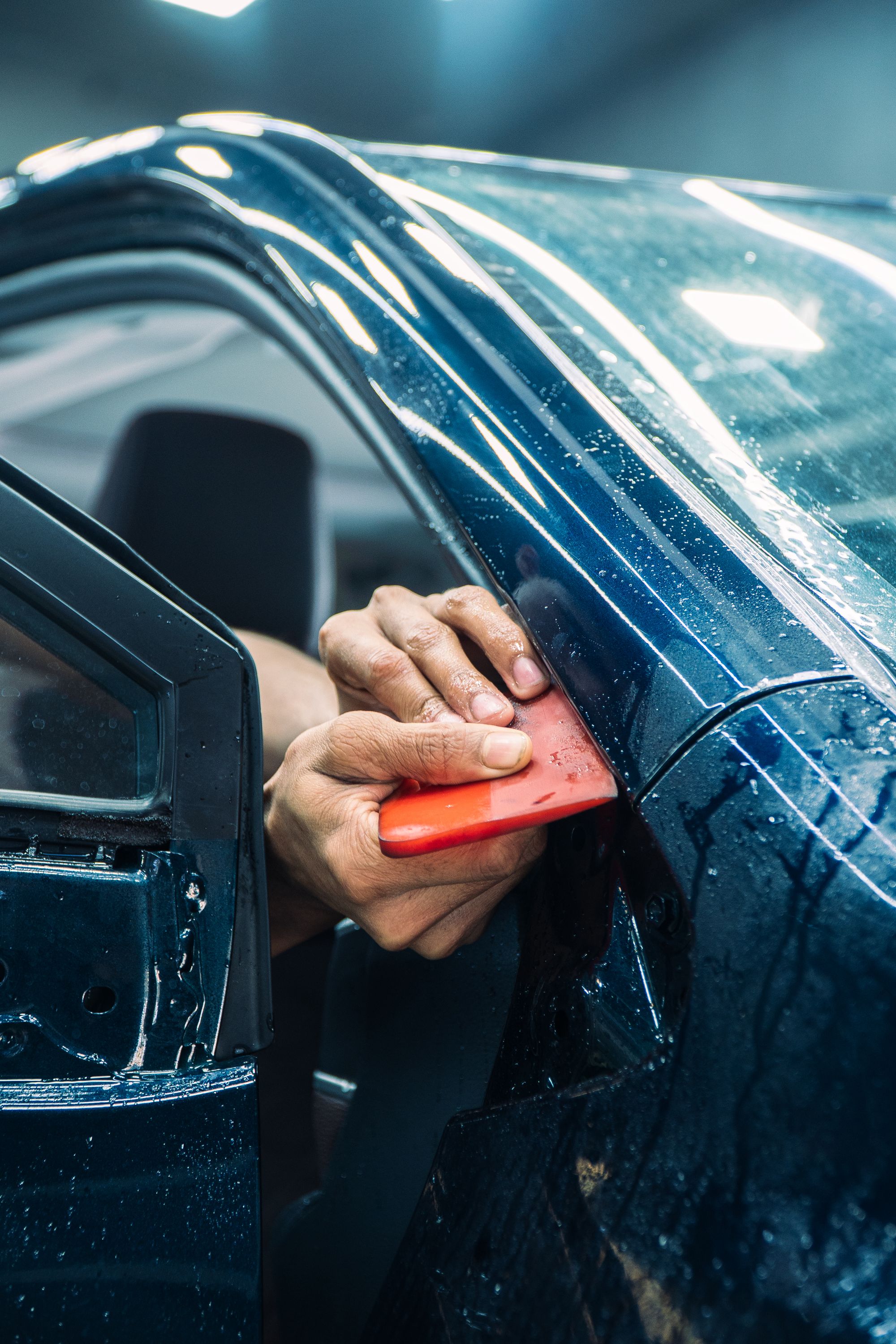 Technician carefully installing clear protection film on a vehicle panel